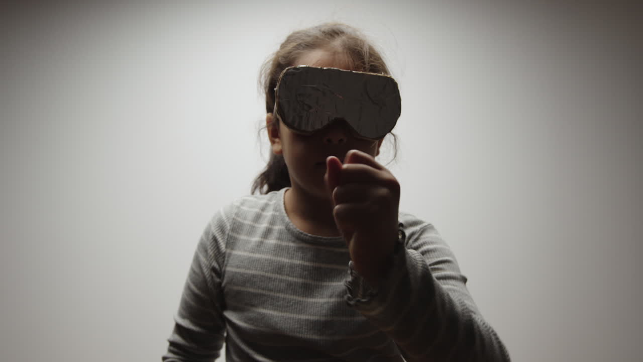 Young Girl Pretends to Play in Virtual Reality Wearing Cardboard Headset