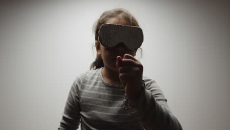 young girl pretends to play in virtual reality wearing cardboard headset
