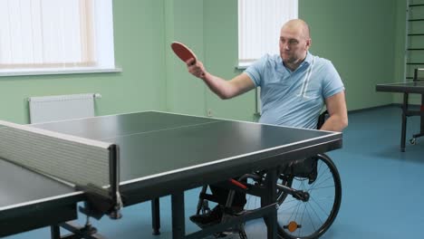 a man in a wheelchair plays ping pong. people with disabilities play table tennis. rehabilitation of the disabled. paralympic sport.