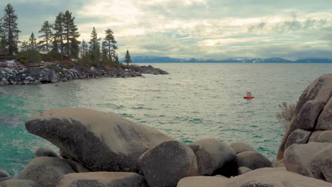 grandes formaciones rocosas con un hermoso lago azul frío rodeado de pinos y montañas y nubes nevadas de la sierra - puerto de arena, lago tahoe sur, nevada - tiro ancho