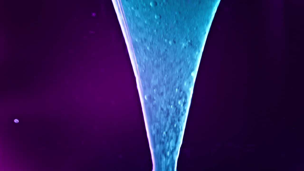 Vibrant liquids swirl and mix in a colorful macro shot with a glowing purple and blue gradient backdrop