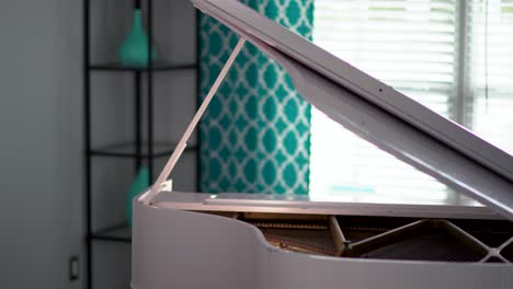 Young-elegant-woman-wearing-gloves-caresses-white-piano-sits-down-and-poses