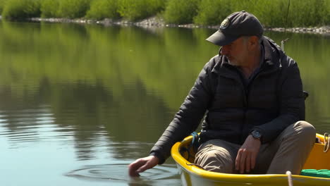 Man in a yellow boat touching the water