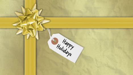 animation of happy holidays text on tag over christmas present with golden ribbon