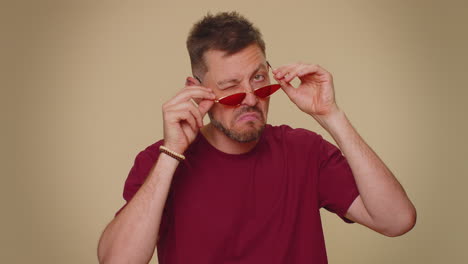 Cheerful-bearded-handsome-stylish-young-man-in-t-shirt-and-red-sunglasses-smiling,-looking-at-camera