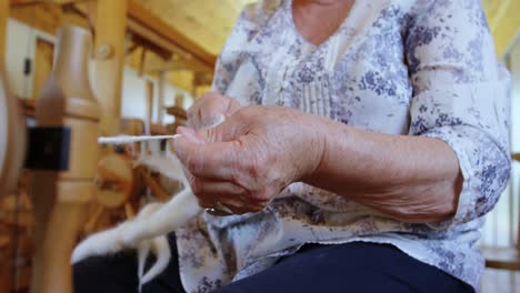 mujer mayor tirando del hilo y haciendo hilo de la máquina de tejer 4k