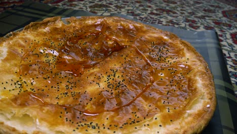 vertiendo jarabe de azúcar sobre un plato de pastelería escamosa de yemen bent al-sahn, postre árabe