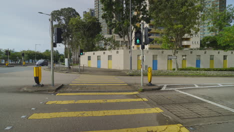 pov walk crossing crosswalk in city of hong kong with high-rise buildings in background near river