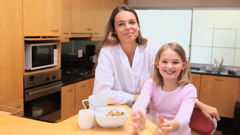 smiling mother and daughter drinking together