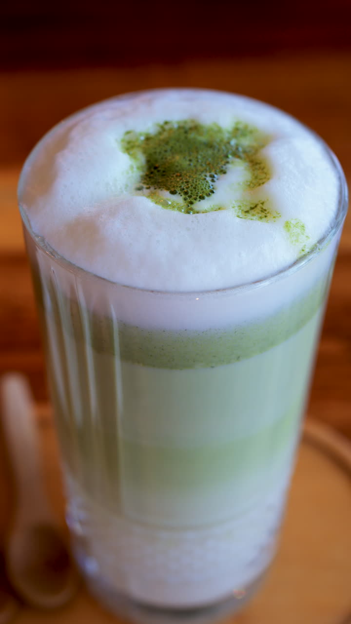 Close up of a matcha latte on a table at a cafe. Vertical