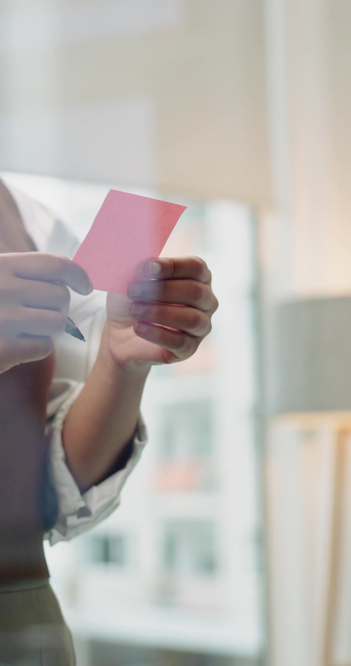 Donna professionista che applica post-it su una parete di vetro in ufficio