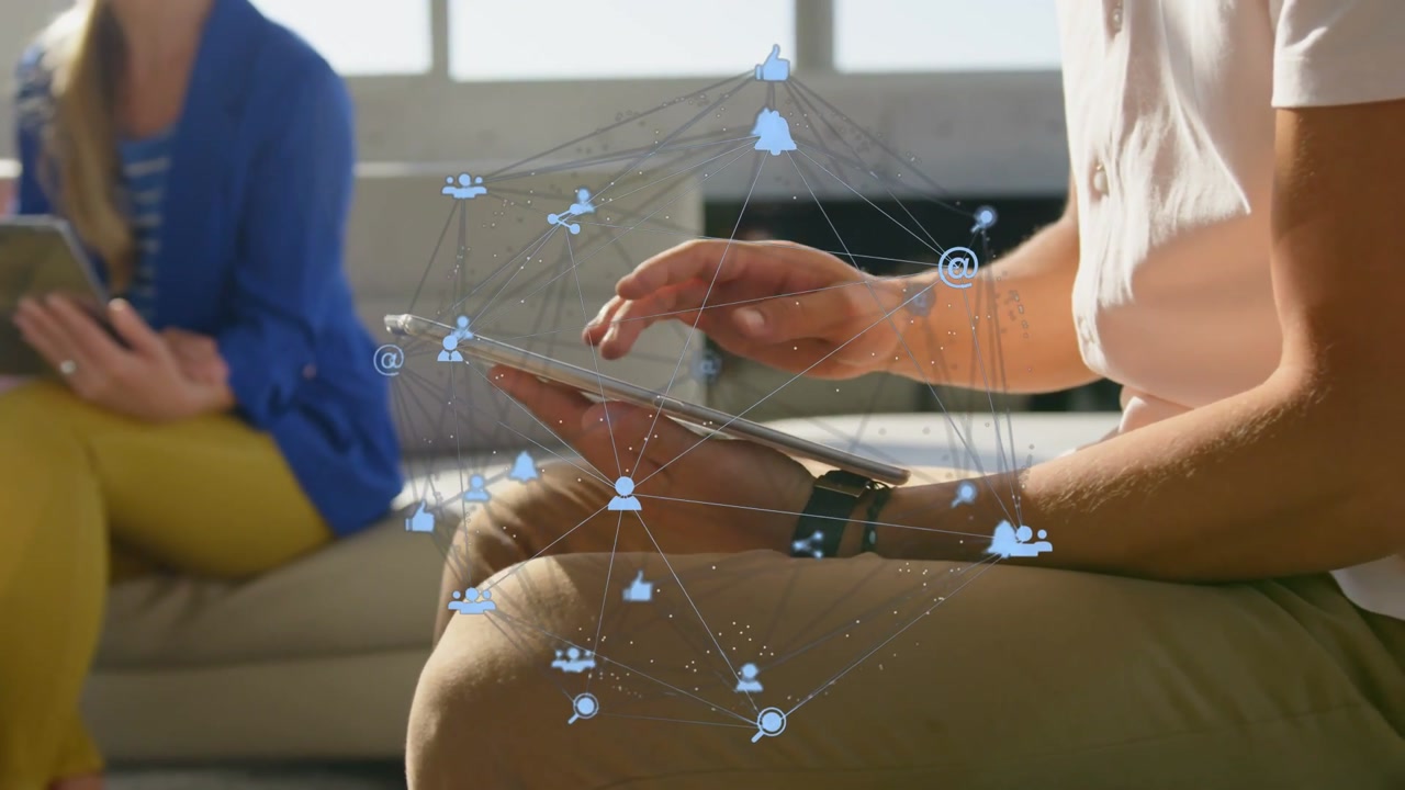 Vertical video: Man tapping and swiping tablet, generating animated icons around lap for marketing