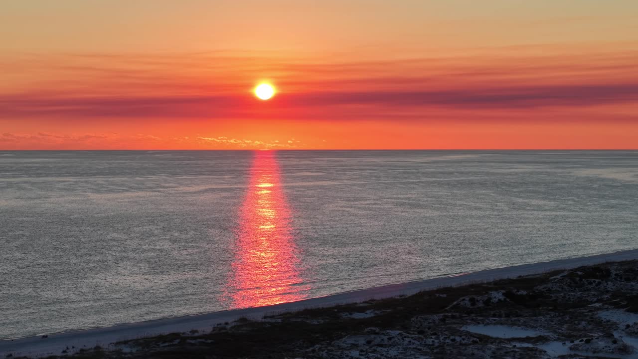 Panoramic drone fly at vibrant sunset moment over calm Gulf of Mexico with reflection on water surface, 30A, Florida, USA