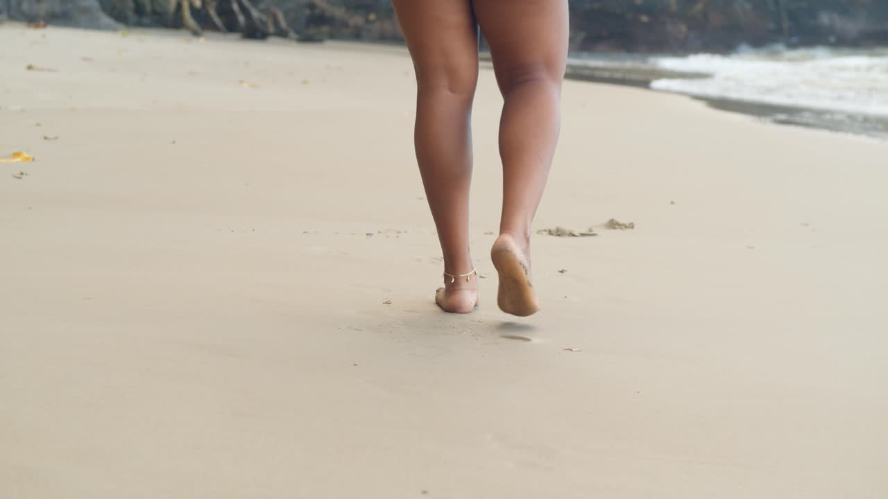 piernas sexy caminando en la playa con un brazalete en el tobillo