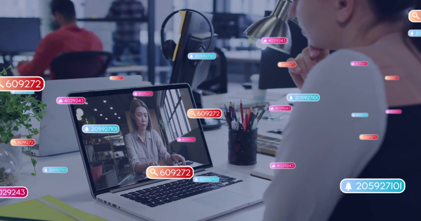 Woman at laptop watching presenter gesturing and causing floating badges showing business feedback