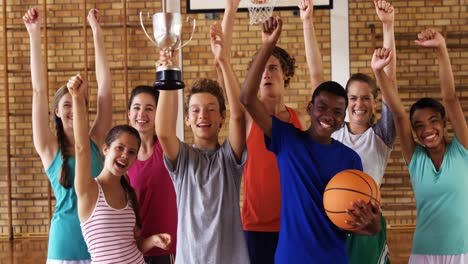 High-school-kids-cheering-while-holding-trophy-in-basketball-court