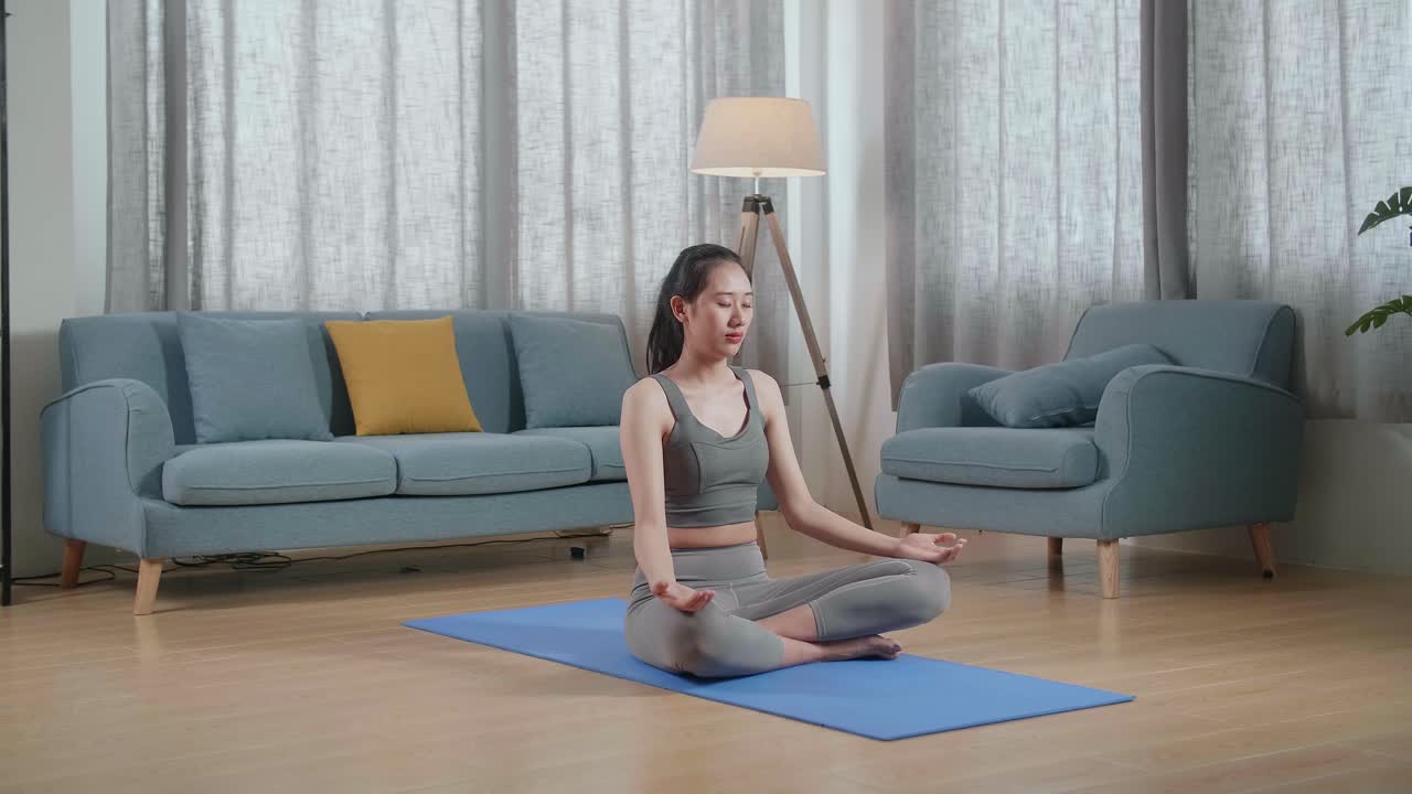 젊은 아시아 운동선수 여성이 집에서 요가 매트에서 운동하는 동안 명상합니다. 건강한 생활 방식, 피트니스, 웰빙 및 마인드풀니스
