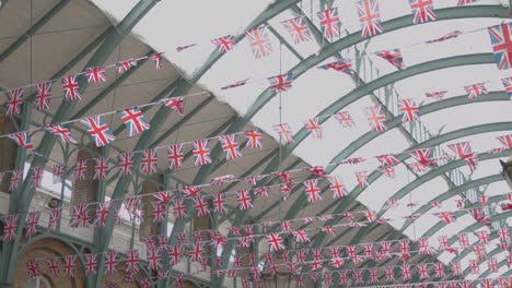 Union-Jack-Flaggen-Schmücken-Den-Covent-Garden-Market-Mit-Touristen-In-London,-Großbritannien