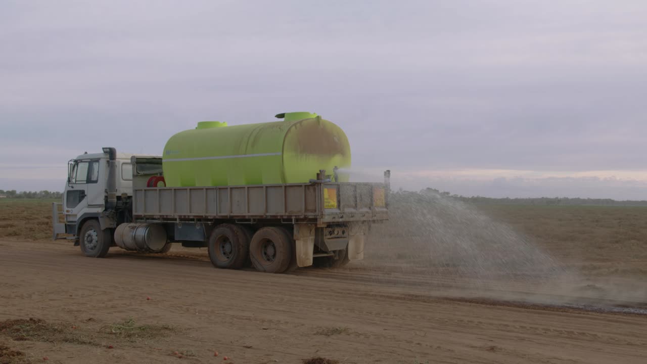 먼지를 막으려는 물 트럭이 카메라에서 멀어집니다.