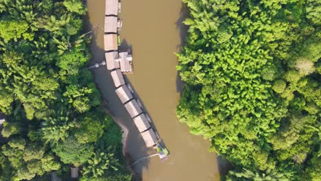 Top-down-aerial-of-River-kwai-floating-hotels-in-brown-river-surrounded-by-jungle