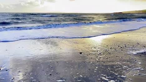 romantic sunset on a sandy beach with waves in ireland, west cork