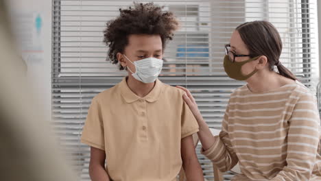 woman and boy wearing masks waiting