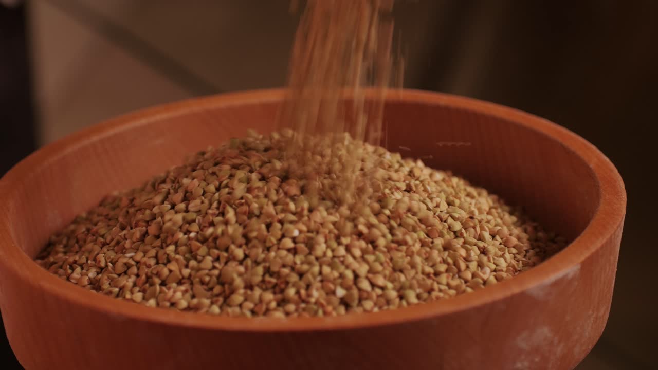 Close-up shot of treatment of seeds of cereals: rye, barley, wheat against diseases and insects using modern equipment. Hard wheat in hopper being ground into whole wheat flour. High quality 4k footage