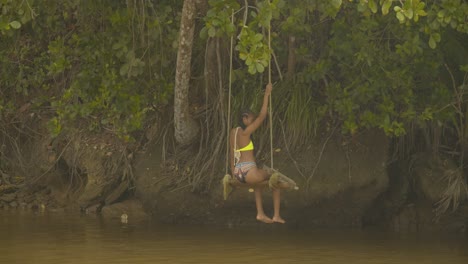 Una-Mujer-Sentada-Y-Columpiándose-En-La-Orilla-Del-Río-Mientras-Se-Divierte