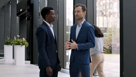 two businessmen talking in office hall