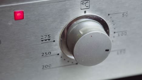 metallic toggle switch of the cooker oven close-up. front panel of modern oven. switching on the stove, baking oven and changing modes in order to preheat and cook meal