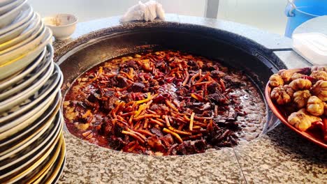 The-cook-fries-lamb-and-stirs-the-meat-with-a-spatula-in-cauldron-close-up