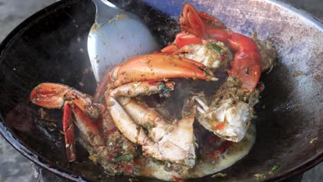 hot and steaming crab meat cooking in wok style pan, close up view