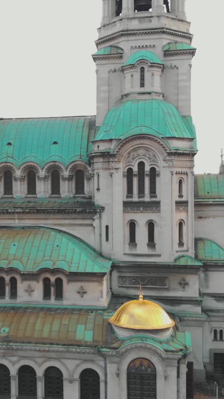 Aerial view of the Alexander Nevsky Cathedral located in Sofia, Bulgaria, highlighting the characteristic green oxidized copper of its roofs. Vertical Video, Rising Shot