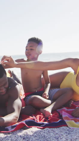 smiling african american family lying on towels on sunny beach