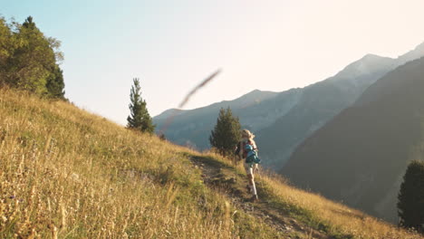 Blonde-woman-hiking-uphill-in-mountains-of-Benasque,-Spain,-slowmo-wide-shot