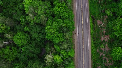 two joggers on rural road running with drone pointed down overhead going over trees