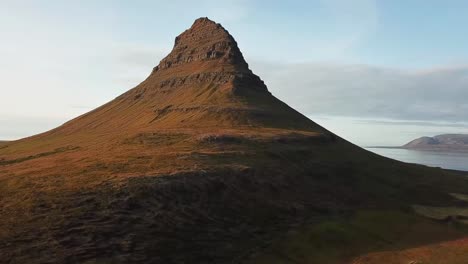Kirkjufell mountain rising majestically in the Icelandic landscape, presenting breathtaking views of the surrounding nature and captivating scenery for nature lovers, drone rising establishing shot
