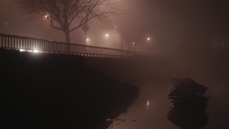 dense fog by riverside headlight light beams through railing wide shot