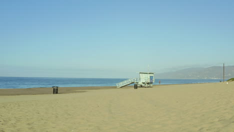 Rückwärts-Dolly-Shot,-Der-Den-Strand-Und-Die-Rettungsschwimmerhütte-Enthüllt