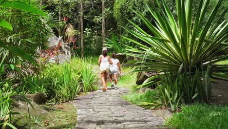 Sisters,-daughters-walking-an-old-concrete-steps-between-plants-inside-the-botanical-garden,-Mahe-Seychelles-2