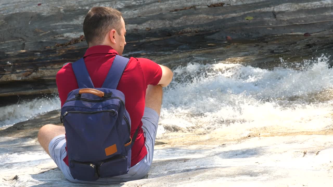 배 을 들고 혼자 여행 하는 남자 는 걱거리는 산 강 근처 에 앉아 있다