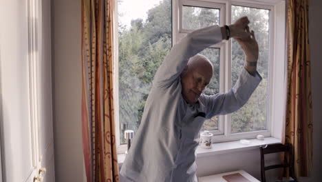 senior man stretching in a bright room