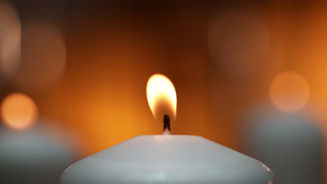 kerzenlicht flackert in langsamer bewegung auf dem warmen orangefarbenen hintergrund in einem tempel