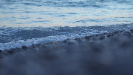 Meerwasserstruktur,-Wellen,-Die-Am-Ufer-Mit-Kiessteinen-Bei-Morgensonne-Schäumen