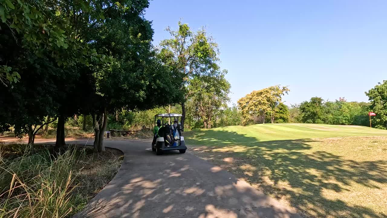 ゴルフカートが茂った木に囲まれた道を走る