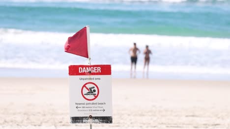 warning sign on beach, people in background