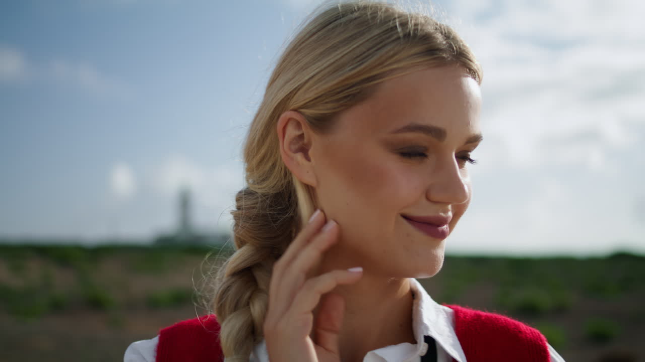 блондинка смотрит в камеру в солнечный день вблизи. молодая леди выпрямляет волосы одна