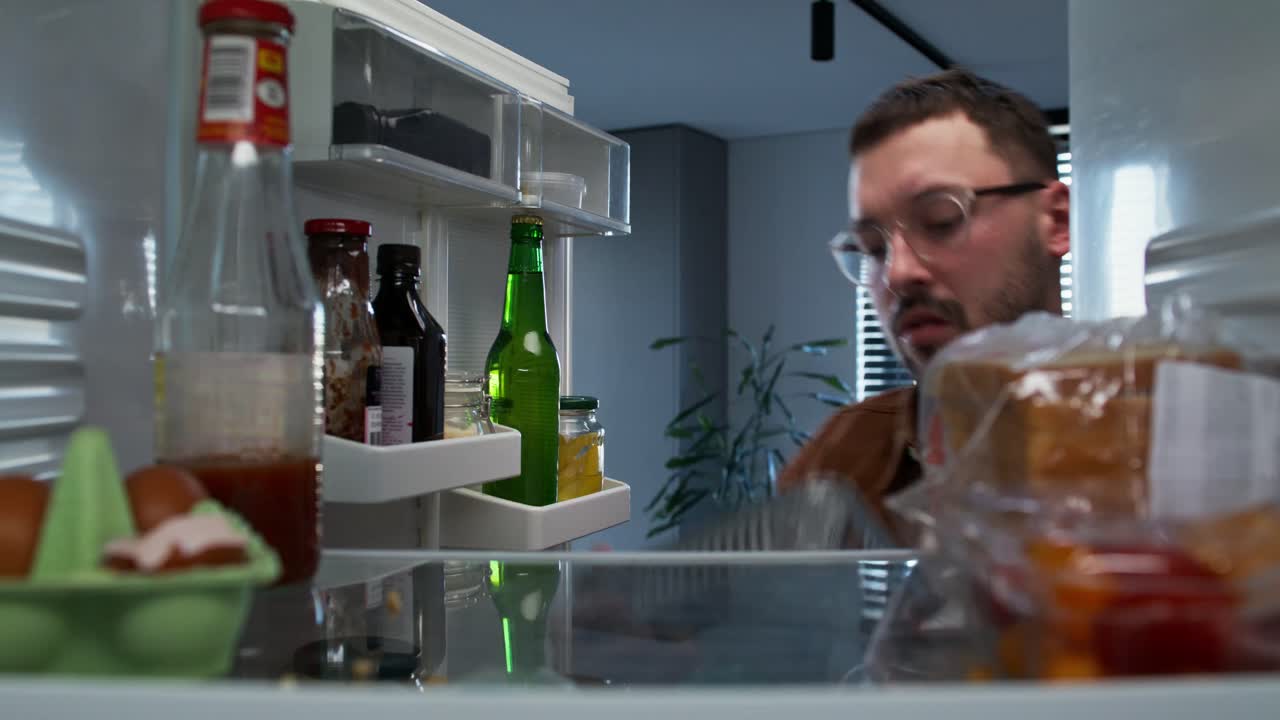 hombre mirando dentro del refrigerador