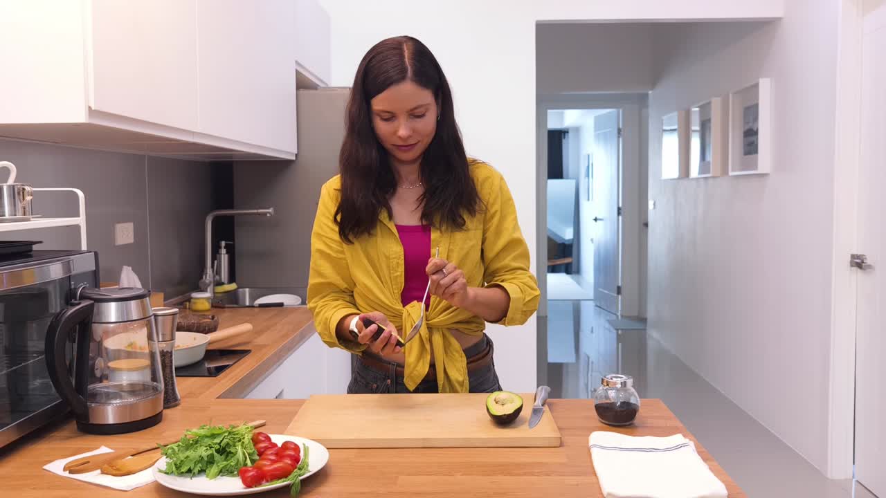 mujer cortando un aguacate en una cocina moderna