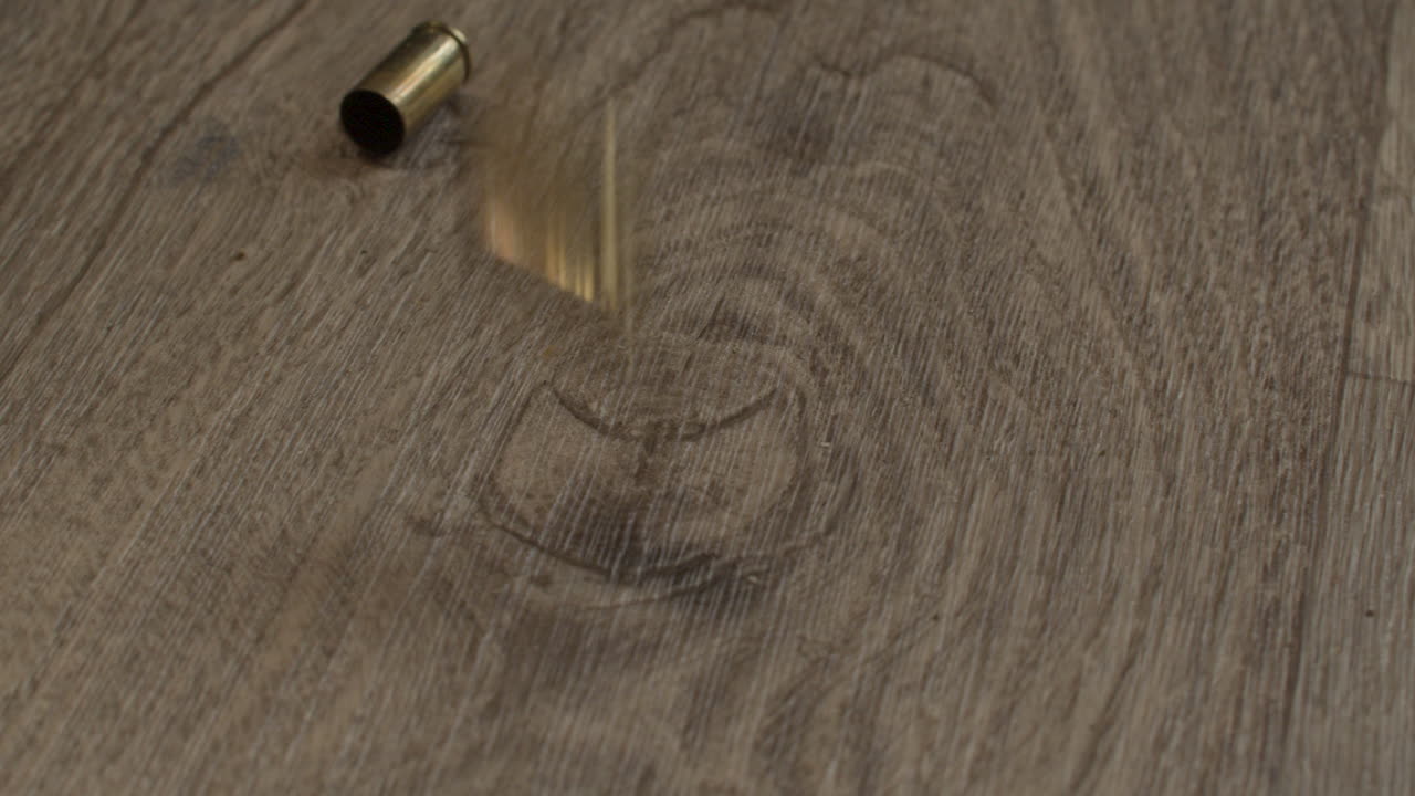 varios casquillos de bala de 9 mm disparados que caen sobre el piso de una sala de estar de madera dura